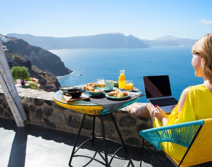 Lady on villa terrace overlooking sea, using WiFi