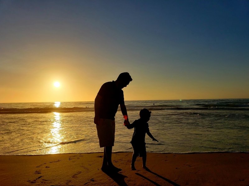 Father and son on beach at sunset