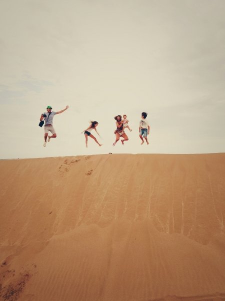 Family jumping on top of sand dune, Spain